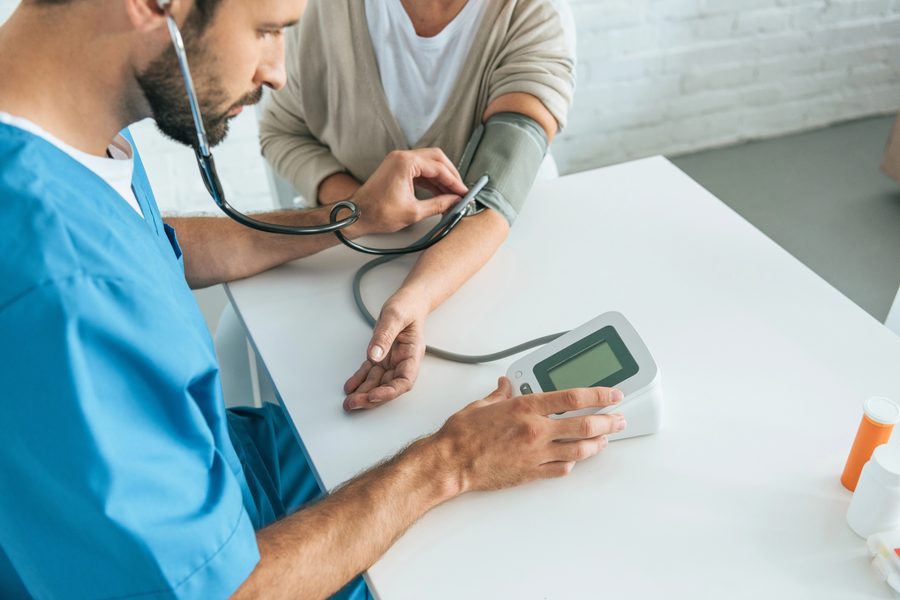 Enfermero tomando la presión arterial a una adulta mayor en una visita domiciliaria